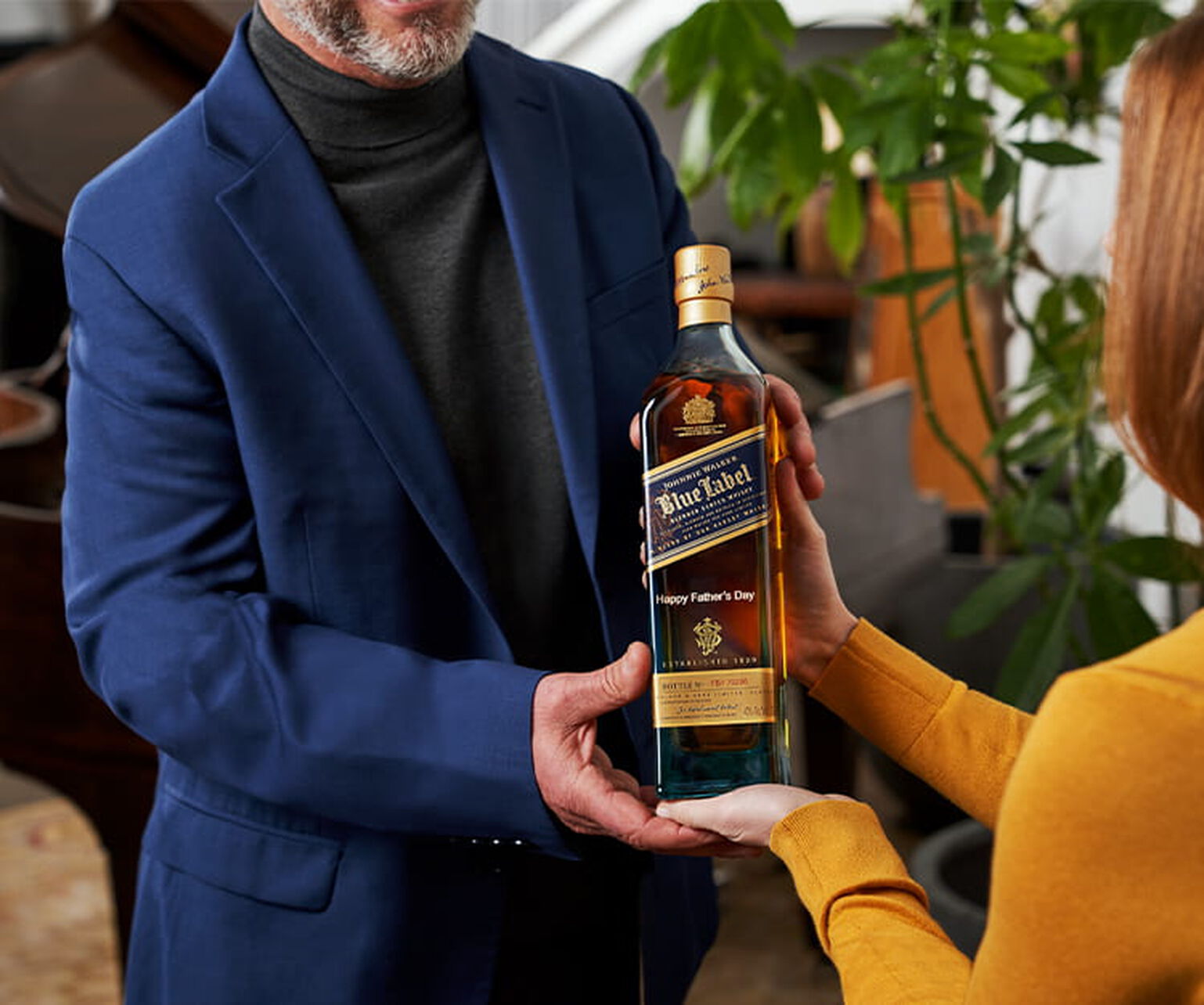 A woman gifting an engraved bottle of Johnnie Walker Blue Label to a father